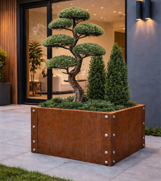 Jardinière carrée en acier Corten renforcée par des boulons et plantée d’un arbre topiaire devant une villa contemporaine.