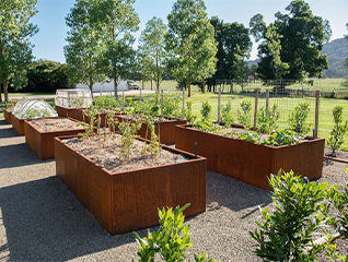 Jardinière Corten carrée basse accueillant des plantes tapissantes et des vivaces dans un aménagement paysager contemporain.