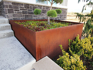 Grande jardinière Corten carrée XXL accueillant un arbre dans un espace public paysager.