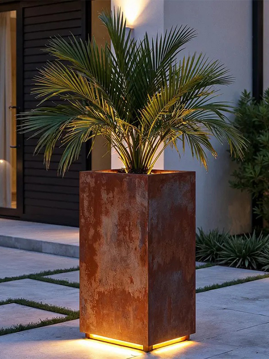 Jardinière Corten rectangulaire haute accueillant un palmier devant l’entrée d’une villa contemporaine au Maroc.